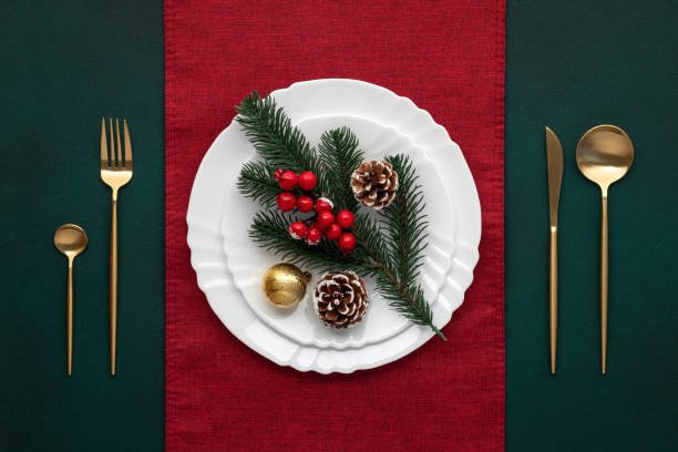 Tovaglia natale elegante in cotone verde e runner rosso con decorazioni natalizie su tavola apparecchiata

