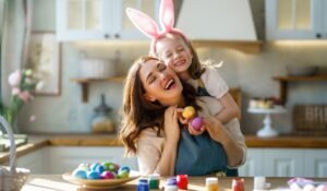 Mamma e bambina preparano Ricette Pasqua bambini con orecchie da coniglio, tavola imbandita di Pasqua