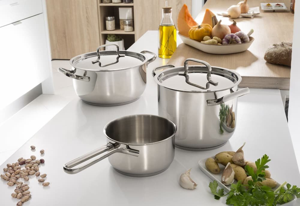 Batteria di pentole in acciaio inox completa con pentole e padelle su piano cottura moderno